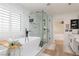 Modern bathroom featuring a soaking tub, glass enclosed shower, and bright white color scheme at 12346 Valley Chase Ave, Las Vegas, NV 89138