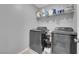 Convenient laundry room with modern washer and dryer, plus shelving for storage at 1606 Wild Grain Ave, North Las Vegas, NV 89086