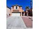 Two story home features tan stucco, two car garage, neutral trim, and desert landscaping at 2316 Cockatoo Dr, North Las Vegas, NV 89084