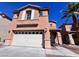 Two story home features tan stucco, two car garage, neutral trim, and desert landscaping at 2316 Cockatoo Dr, North Las Vegas, NV 89084