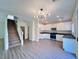 Open floor plan with wood vinyl flooring leading to kitchen with stainless appliances and white cabinets at 2316 Cockatoo Dr, North Las Vegas, NV 89084