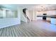 Open floor plan with wood vinyl flooring leading to kitchen with stainless appliances and white cabinets at 2316 Cockatoo Dr, North Las Vegas, NV 89084