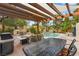 Outdoor kitchen and dining area with grill, fireplace and pool views under a pergola at 4195 Balmoral Castle Ct, Las Vegas, NV 89141