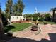 Charming backyard features a lush lawn, desert landscaping, fire pit, and quaint fountain at 442 Beardsley Cir, Henderson, NV 89052