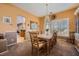 Well-lit dining room with large window, chandelier, and a view into the kitchen at 442 Beardsley Cir, Henderson, NV 89052