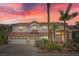 Inviting two-story home with a three-car garage, desert landscaping, and a red tile roof against a colorful sunset at 442 Beardsley Cir, Henderson, NV 89052
