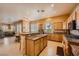 Traditional kitchen with wood cabinets, granite countertops, and an island with bar seating open to the living room at 442 Beardsley Cir, Henderson, NV 89052
