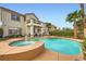 Backyard pool and jacuzzi features desert landscaping, mature palm trees, and covered patio at 442 Beardsley Cir, Henderson, NV 89052