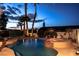 Backyard pool and jacuzzi features desert landscaping and mature palm trees, all lit at dusk at 442 Beardsley Cir, Henderson, NV 89052