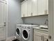 Efficient laundry room with modern washer and dryer, white cabinets, countertop, and utility sink for added convenience at 5518 Stormy Night Ct, Las Vegas, NV 89120