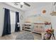 Bright Bedroom featuring a crib, accent wall with desert themed mural and window at 6312 Monarch Creek St, Las Vegas, NV 89130