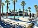 Community pool area featuring palm trees, lounge chairs and tables under a bright blue sky at 6436 Linden St, North Las Vegas, NV 89086