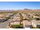 Expansive aerial view showcases a neighborhood of single-Gathering homes, set against a backdrop of mountains and clear blue skies at 9807 Sage Canyon St, Las Vegas, NV 89178