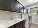 Convenient laundry room with sink, countertop, cabinets, window, and modern washer and dryer at 9807 Sage Canyon St, Las Vegas, NV 89178