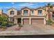 Two-story tan home featuring a tile roof, balcony, paver driveway and a two-car garage with arched windows at 9967 Pipestone St, Las Vegas, NV 89141