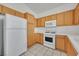 Well-equipped kitchen featuring wooden cabinetry, modern white appliances, and durable tile flooring at 100 Beaver Falls Ave, Las Vegas, NV 89123