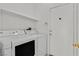 Bright laundry room featuring a white washer and dryer, storage shelf and a convenient entryway door at 100 Beaver Falls Ave, Las Vegas, NV 89123