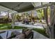 Covered patio with seating area overlooks backyard oasis with pool, rock waterfall, and lush landscaping at 1301 Kingdom St, Las Vegas, NV 89117