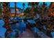 Expansive backyard with a pool, a gazebo, a water slide, and palm trees decorated with lights at 1301 Kingdom St, Las Vegas, NV 89117