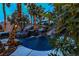 Serene pool area with rock formations, a water slide, and palm trees wrapped in decorative lights at 1301 Kingdom St, Las Vegas, NV 89117