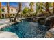 Sparkling pool with rock waterfall and view of the house and covered patio at 1301 Kingdom St, Las Vegas, NV 89117