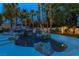 Stunning backyard pool with rock features, a water slide, and palm trees adorned with string lights at 1301 Kingdom St, Las Vegas, NV 89117