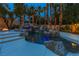 Beautiful pool with a slide, rock features, and palm trees adorned with lights enhancing the ambiance at 1301 Kingdom St, Las Vegas, NV 89117