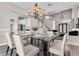 Dining room with modern chandelier, glass table, white chairs and open floor plan at 3088 Via Flaminia Ct, Henderson, NV 89052