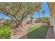 Backyard featuring desert landscaping, synthetic grass, and a stone retaining wall at 4956 Momenti St, Las Vegas, NV 89135