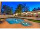 Serene backyard with a luxurious pool and spa, accented by landscaped walls, lighting and mature trees at 6129 Flaming Arrow Rd, North Las Vegas, NV 89031