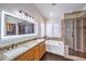 Spacious bathroom with granite counters, double sinks, soaking tub, and glass-enclosed shower at 6129 Flaming Arrow Rd, North Las Vegas, NV 89031