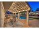 Charming covered patio with string lights, built-in grill, and seating area, perfect for outdoor entertaining by the pool at 6129 Flaming Arrow Rd, North Las Vegas, NV 89031