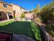 Spacious backyard with manicured artificial grass, a brick retaining wall, and a charming covered patio at 6656 Fort William St, North Las Vegas, NV 89084