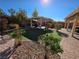 Charming backyard with lush landscaping, a covered patio, artificial turf, and a brick patio area at 6656 Fort William St, North Las Vegas, NV 89084