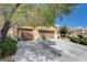 Wide driveway leading to a three-car garage, framed by lush greenery and mature trees at 6656 Fort William St, North Las Vegas, NV 89084