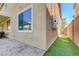 Exterior shot of the stucco siding with a view of the covered patio and backyard with brick pavers and turf at 6656 Fort William St, North Las Vegas, NV 89084