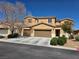 Tan two-story home featuring a two-car garage, manicured front yard with shrubs, and a well-maintained desert landscape at 6656 Fort William St, North Las Vegas, NV 89084