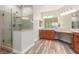 Modern bathroom featuring a glass enclosed shower, double sinks, and warm wood cabinetry at 7338 Flying Pegasus Ct, Las Vegas, NV 89131