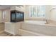 Luxurious primary bathroom boasting a soaking tub, a fireplace, and travertine tile surround at 7338 Flying Pegasus Ct, Las Vegas, NV 89131