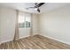Bright bedroom with wood-look flooring, a ceiling fan, and a window with plantation shutters at 7338 Flying Pegasus Ct, Las Vegas, NV 89131