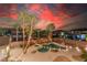 Aerial view of a beautiful backyard pool and spa, surrounded by palm trees and string lights at sunset at 7338 Flying Pegasus Ct, Las Vegas, NV 89131