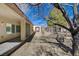 View of the side yard featuring decorative rock, a mature tree, and a partial covered patio at 7564 Wingspread St, North Las Vegas, NV 89084