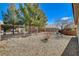 A landscaped backyard with decorative rock, mature trees, and a metal fence line at 7564 Wingspread St, North Las Vegas, NV 89084