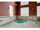 Indoor hot tub with tile accents, brick walls, chair, and glass block window at 7564 Wingspread St, North Las Vegas, NV 89084