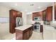 A well-lit kitchen featuring dark wood cabinetry, stainless steel appliances, and a kitchen island at 7904 Fantail Dr, North Las Vegas, NV 89084
