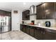 Modern kitchen with dark wood cabinets, stainless steel appliances, granite countertops, and tile backsplash at 9120 Mastodon Ave, Las Vegas, NV 89149