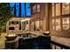 Evening shot of a backyard oasis, complete with a pool, spa, fire bowls, and covered seating area at 10671 Capesthorne Way, Las Vegas, NV 89135