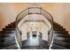 Grand foyer with a curved staircase, dark wood floors, and views into the elegant dining room at 10671 Capesthorne Way, Las Vegas, NV 89135