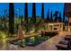Swimming pool at night featuring in-pool seating, outdoor fireplace, and landscaped border at 10671 Capesthorne Way, Las Vegas, NV 89135