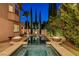 Backyard shot of a pool featuring a jacuzzi with fire bowls, in-pool seating, and a covered patio at 10671 Capesthorne Way, Las Vegas, NV 89135